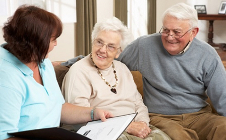 Image shows two older people sitting on a couch, speaking with an advisor.
