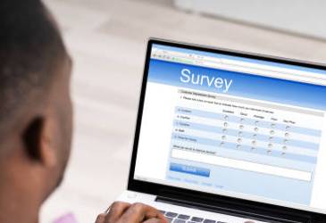 Image shows a man at a laptop filling in a survey.