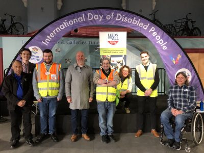 Image shows some of the IDODP 2023 team in front of the Purple International Day of Disabled People arched banner. From left to right is David Blythe of William Merritt Centre, Counsellor Kevin Ritchie who spoke at the event, Robert Stephens of Forum Central, Geoff Turnbull of Leeds City Council, Shaun Webster of Forum Central, Helen Brand who is the Physical and Sensory Impairment lead at Forum Central, Brendan Tannam of Leeds City Council and guest speaker Craig Grimes.