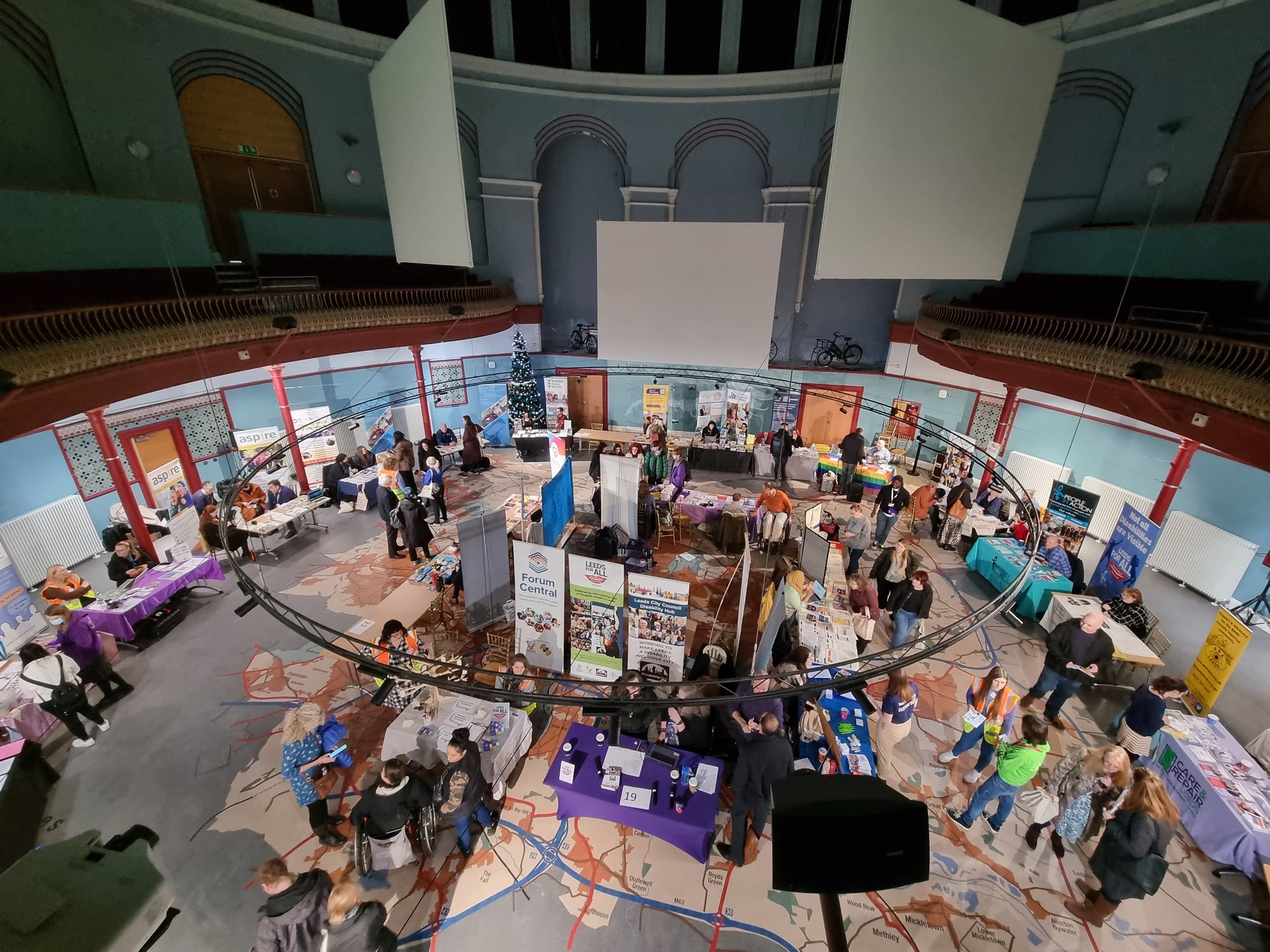 Photo of the Broderick Hall from the second floor balcony in Leeds City Museum showing the Leeds for all marketplace event from above with lots of people and stalls