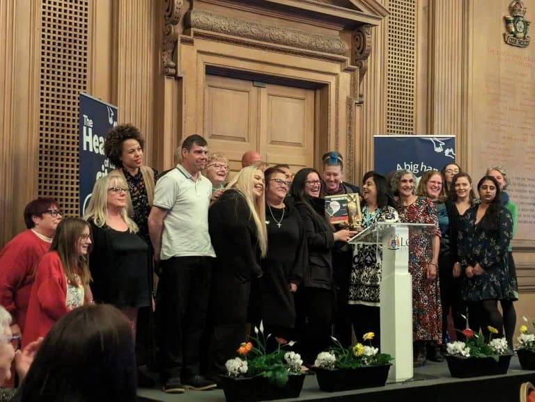 Image shows the Warm Spaces team stood on stage accepting their award.